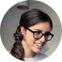 Woman eye glass with wearing a light gray sweater against a neutral background